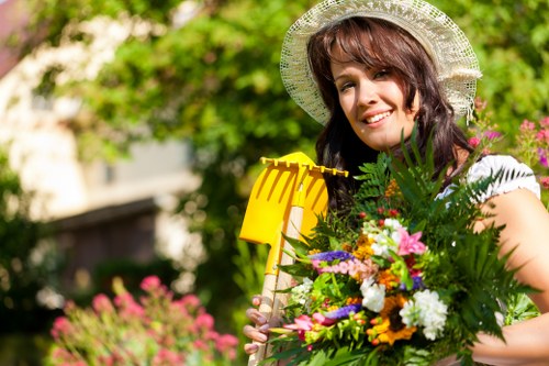 Gardener pruning shrubs and maintaining garden beds